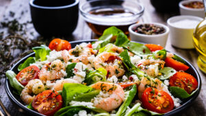 A plate of shrimp salad with tomatoes and spinach.