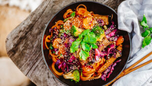 A bowl of food with broccoli, carrots and sesame seeds.